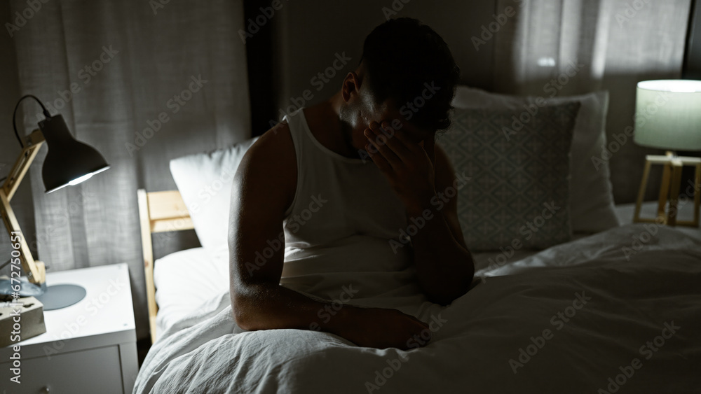 Young arab man stressed sitting on bed at bedroom