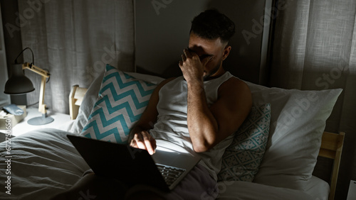 Young arab man using laptop sitting on bed stressed at bedroom