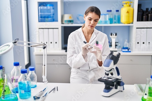 Young beautiful hispanic woman scientist writing mark on sample at laboratory