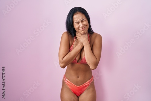 Hispanic woman wearing bikini shouting suffocate because painful strangle. health problem. asphyxiate and suicide concept.