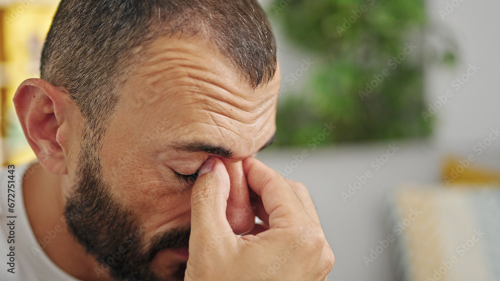 Obraz premium Young hispanic man crying sitting on the sofa at home