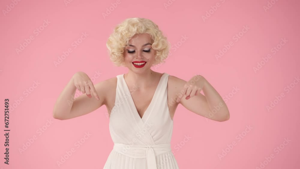 Woman covering her mouth with hands, pointing down with index fingers, nodding her head approvingly, recommending. Woman in the look of in studio on pink background. Advertising, promo. Woman covering her mouth with hands, pointing down with index fingers, nodding her head approvingly, recommending. Woman in the look of in studio on pink background. Advertising, promo.