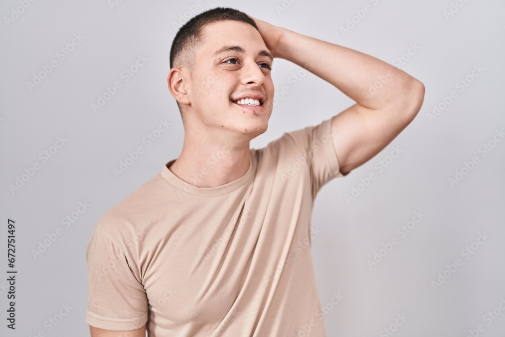 Young man standing over isolated background smiling confident touching hair with hand up gesture, posing attractive and fashionable Young man standing over isolated background smiling confident touching hair with hand up gesture, posing attractive and fashionable