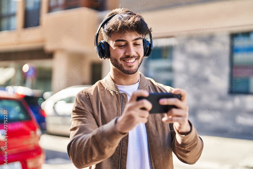 Young hispanic man smiling confident playing video game at street Young hispanic man smiling confident playing video game at street