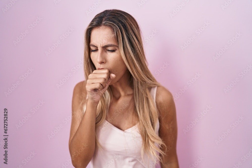 Young blonde woman standing over pink background feeling unwell and coughing as symptom for cold or bronchitis. health care concept. Young blonde woman standing over pink background feeling unwell and coughing as symptom for cold or bronchitis. health care concept.