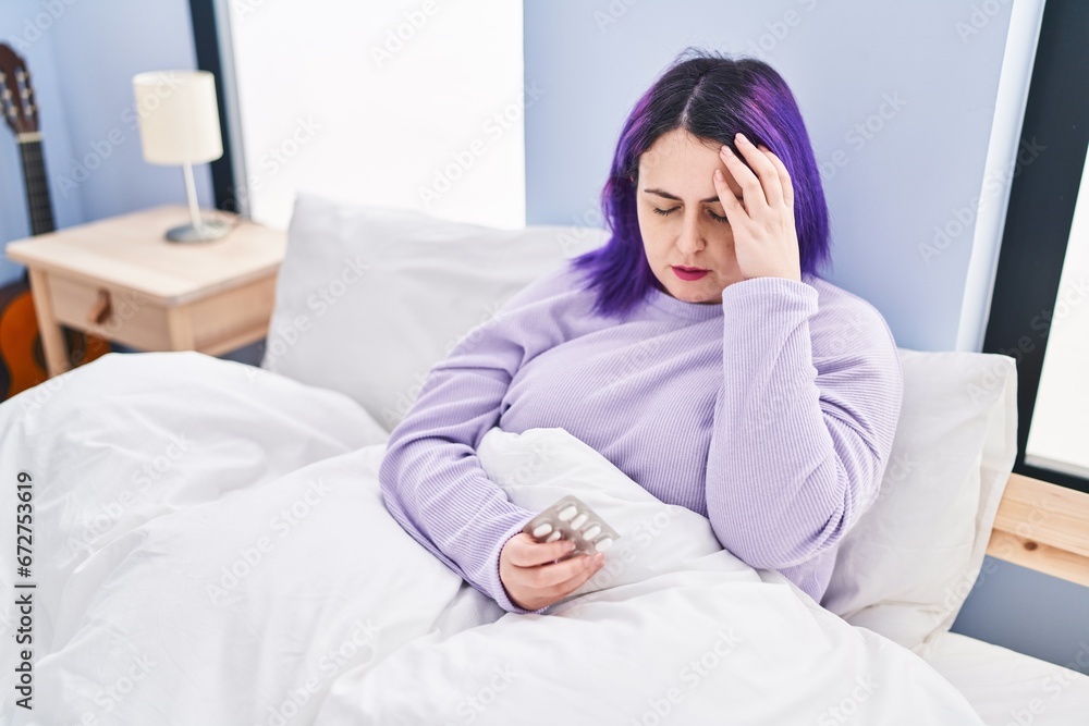Young beautiful plus size woman taking pills for headache sitting on bed at bedroom Young beautiful plus size woman taking pills for headache sitting on bed at bedroom