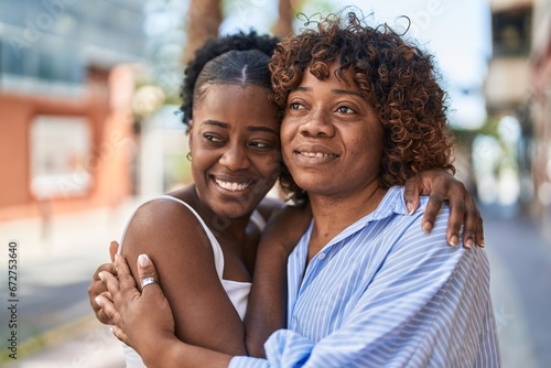 African american women mother and daughter hugging each other at street