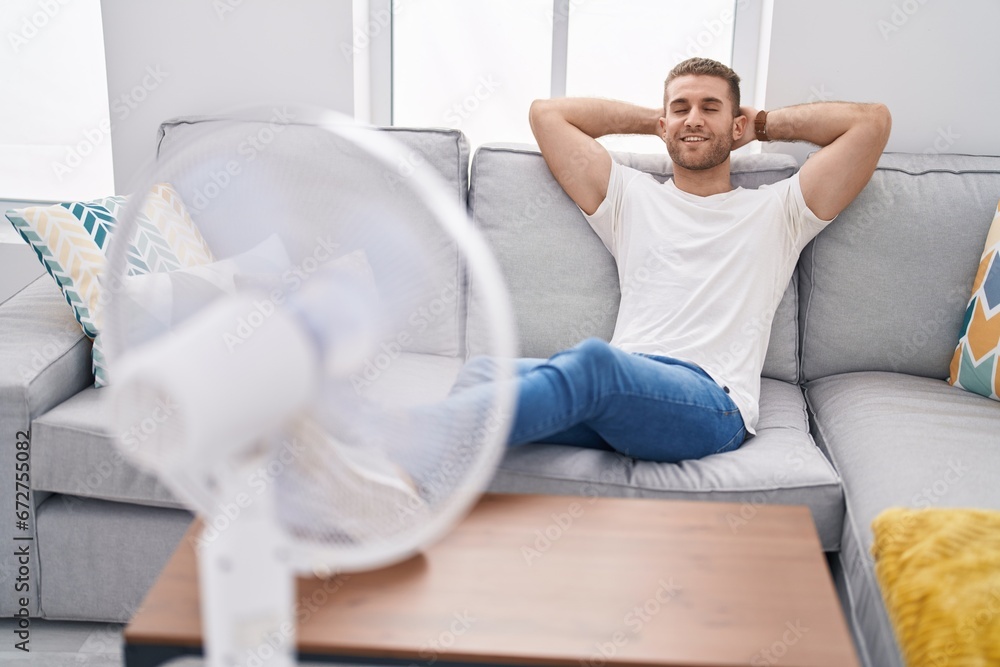 Young caucasian man using ventilator sitting on sofa at home Young caucasian man using ventilator sitting on sofa at home