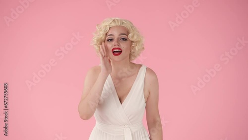 Woman putting her hand to her mouth that screams, calling someone. Woman in the look of in the studio on a pink background. photo