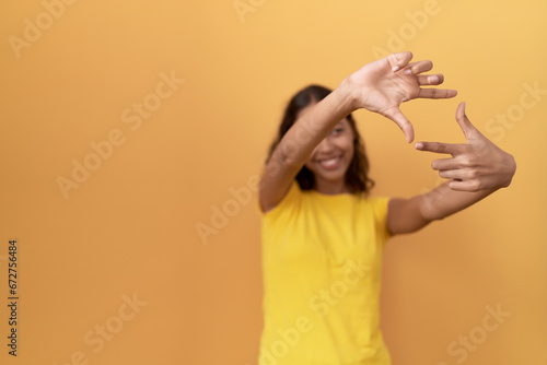 Young african american woman smiling confident doing photo gesture with hands over isolated yellow background