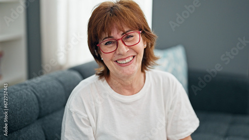 Middle age woman wearing glasses sitting on sofa home