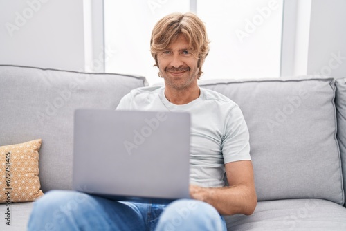 Young man using laptop sitting on sofa at home