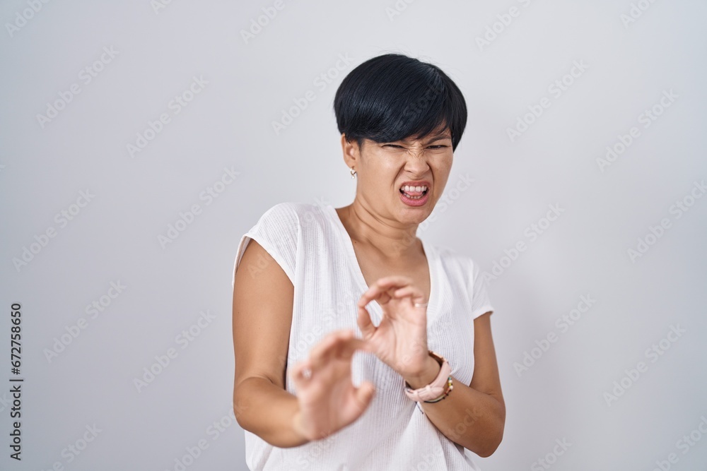 Young asian woman with short hair standing over isolated background ...