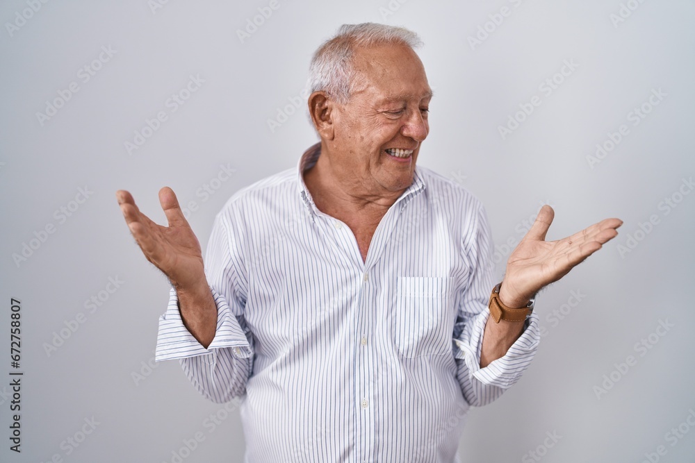 Senior man with grey hair standing over isolated background smiling showing both hands open palms, presenting and advertising comparison and balance Senior man with grey hair standing over isolated background smiling showing both hands open palms, presenting and advertising comparison and balance