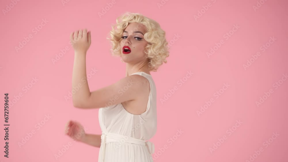 Elegant woman in the image of showing off her biceps. Profile portrait of fragile beautiful woman showing strong arm muscles in studio on pink background. Elegant woman in the image of showing off her biceps. Profile portrait of fragile beautiful woman showing strong arm muscles in studio on pink background.