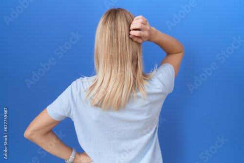 Young caucasian woman wearing casual blue t shirt backwards thinking about doubt with hand on head
