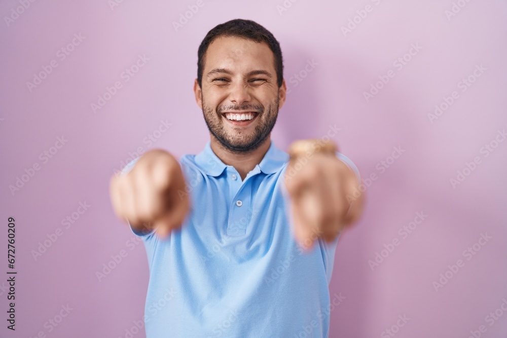 Hispanic man standing over pink background pointing to you and the camera with fingers, smiling positive and cheerful Hispanic man standing over pink background pointing to you and the camera with fingers, smiling positive and cheerful