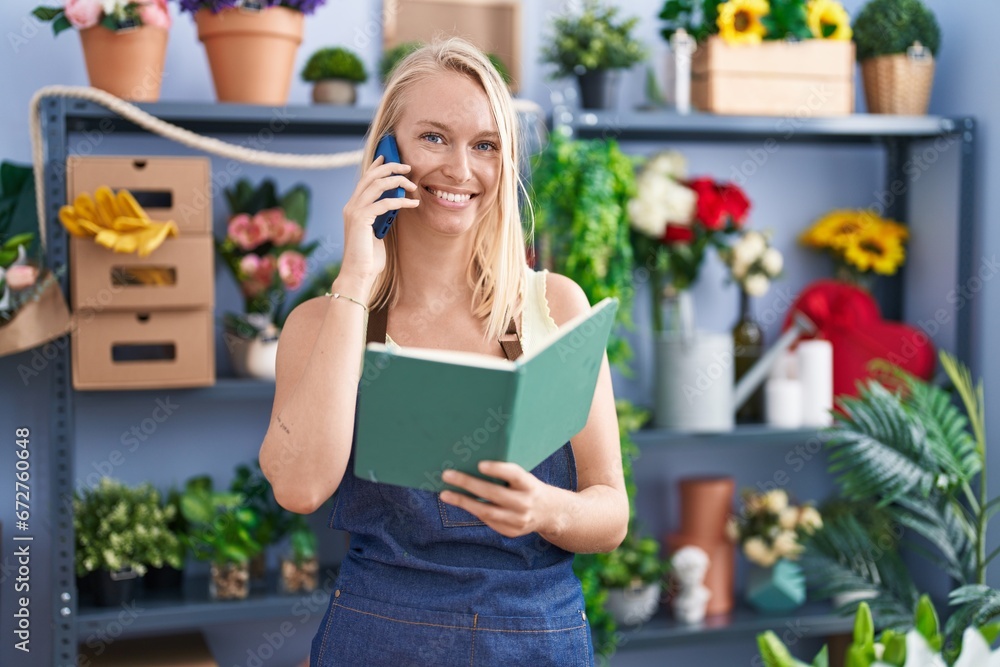 Young blonde woman florist talking on smartphone reading book at florist store Young blonde woman florist talking on smartphone reading book at florist store