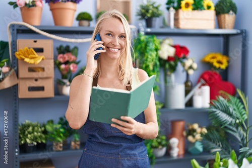 Young blonde woman florist talking on smartphone reading book at florist store