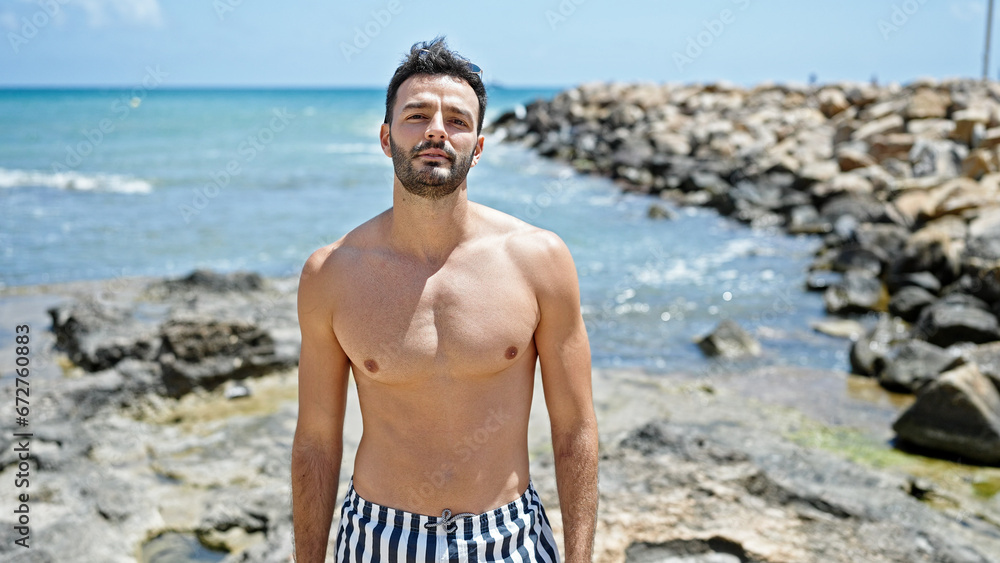 Young hispanic man tourist wearing swimsuit standing at the beach