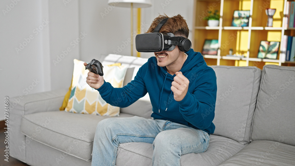 Obraz premium Young hispanic man playing video game using joystick and virtual reality glasses at home