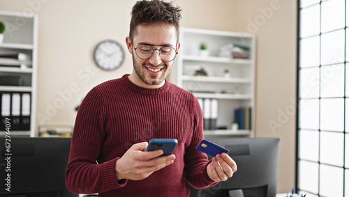 Young hispanic man business worker shopping with smartphone and credit card at office