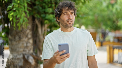 Young hispanic man smiling confident having free hands call at park