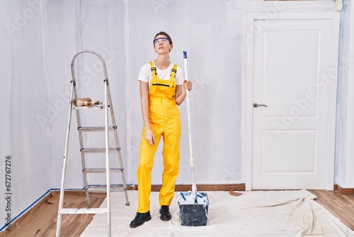 Young caucasian woman painting walls looking sleepy and tired, exhausted for fatigue and hangover, lazy eyes in the morning.