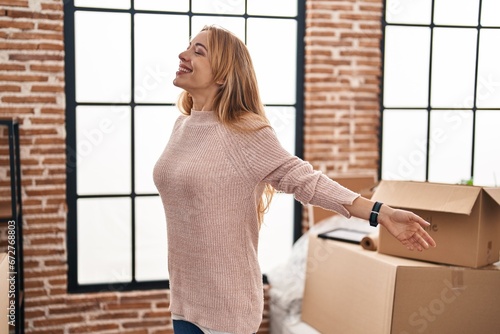 Young woman smiling confident standing with arms open at new home