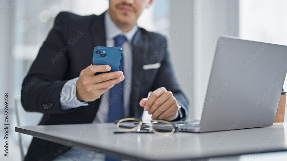 Young hispanic man business worker using laptop and smartphone at office Young hispanic man business worker using laptop and smartphone at office
