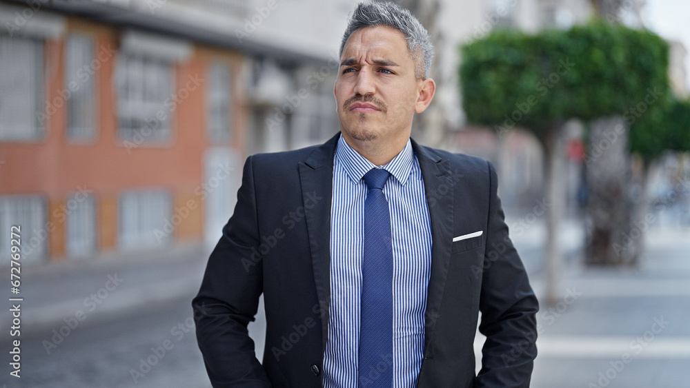 Young hispanic man business worker standing with serious face at street Young hispanic man business worker standing with serious face at street