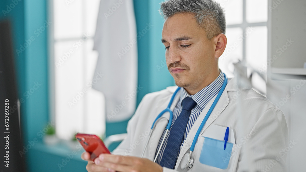 Young hispanic man doctor using computer and smartphone at clinic Young hispanic man doctor using computer and smartphone at clinic