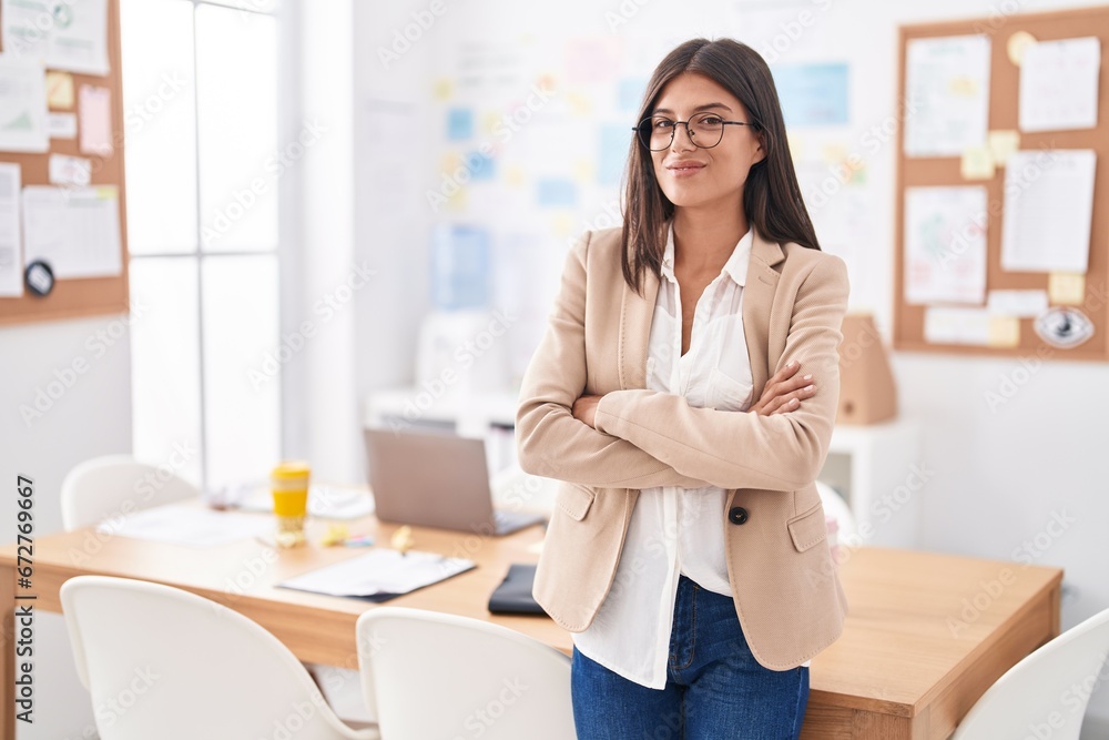 Young beautiful hispanic woman business worker smiling confident standing with arms crossed gesture at office