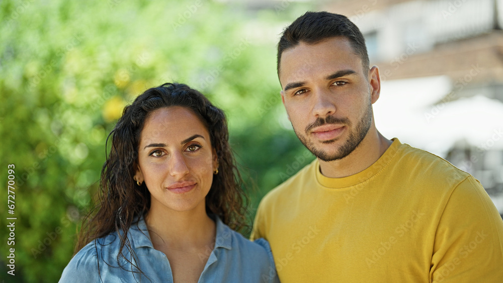 Man and woman couple standing together with relaxed face at park Man and woman couple standing together with relaxed face at park