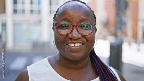 Confident african american woman standing on urban street, radiating joy and positivity, her contagious laughter spreading happiness. her braids bouncing, glasses glinting, truly loving life.
