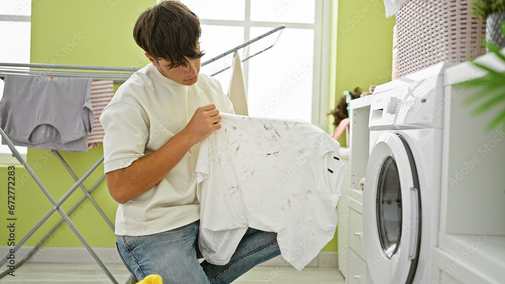 Hispanic young teenager seriously concentrating on tackling a dirty t-shirt stain, primed to clean it in the laundry room at home Hispanic young teenager seriously concentrating on tackling a dirty t-shirt stain, primed to clean it in the laundry room at home