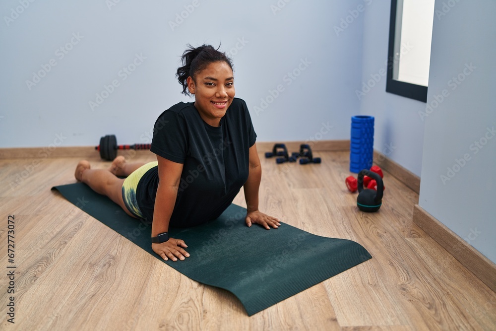 Fototapeta premium Young beautiful latin woman smiling confident stretching back at sport center