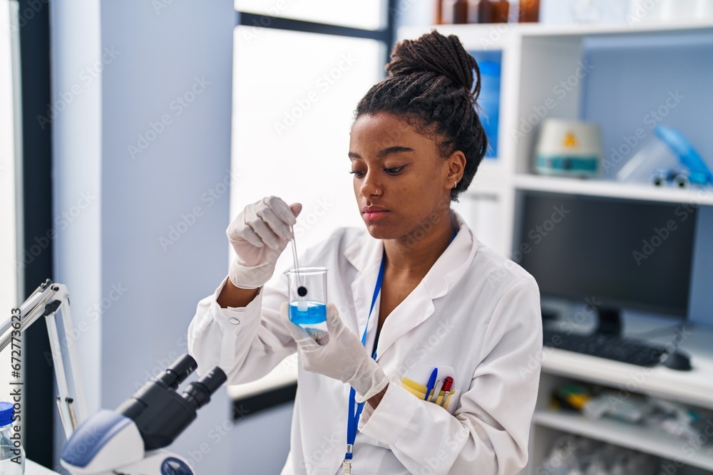 African american woman scientist mixing liquid on glass at laboratory African american woman scientist mixing liquid on glass at laboratory