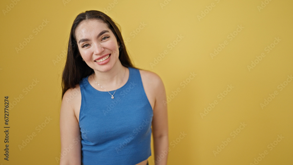 Obraz premium Young beautiful hispanic woman smiling confident standing over isolated yellow background