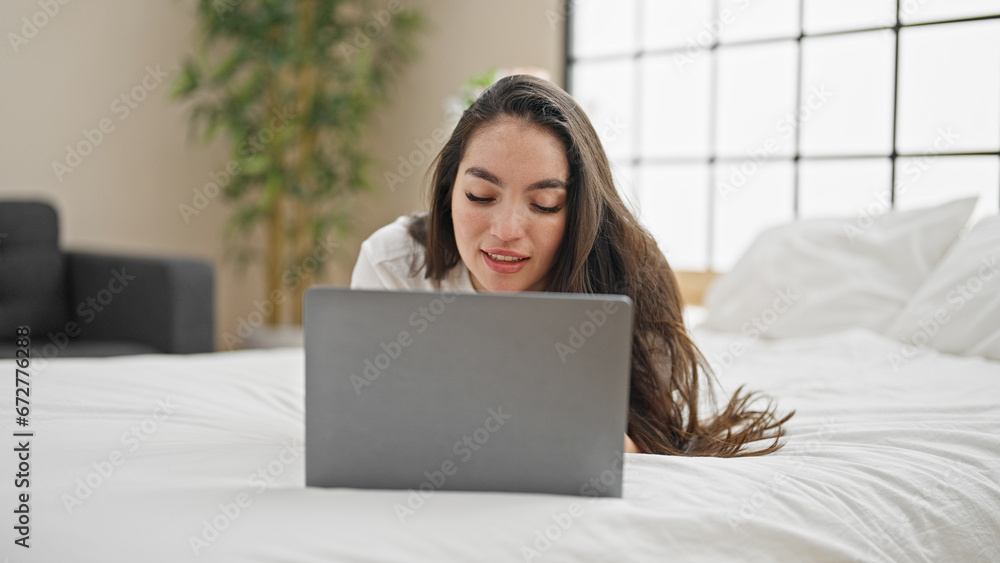 Young beautiful hispanic woman using laptop lying on bed at bedroom Young beautiful hispanic woman using laptop lying on bed at bedroom
