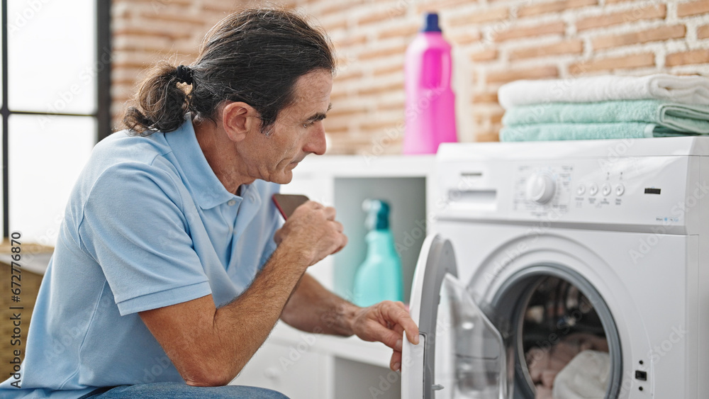 Middle age man washing clothes at laundry room Middle age man washing clothes at laundry room