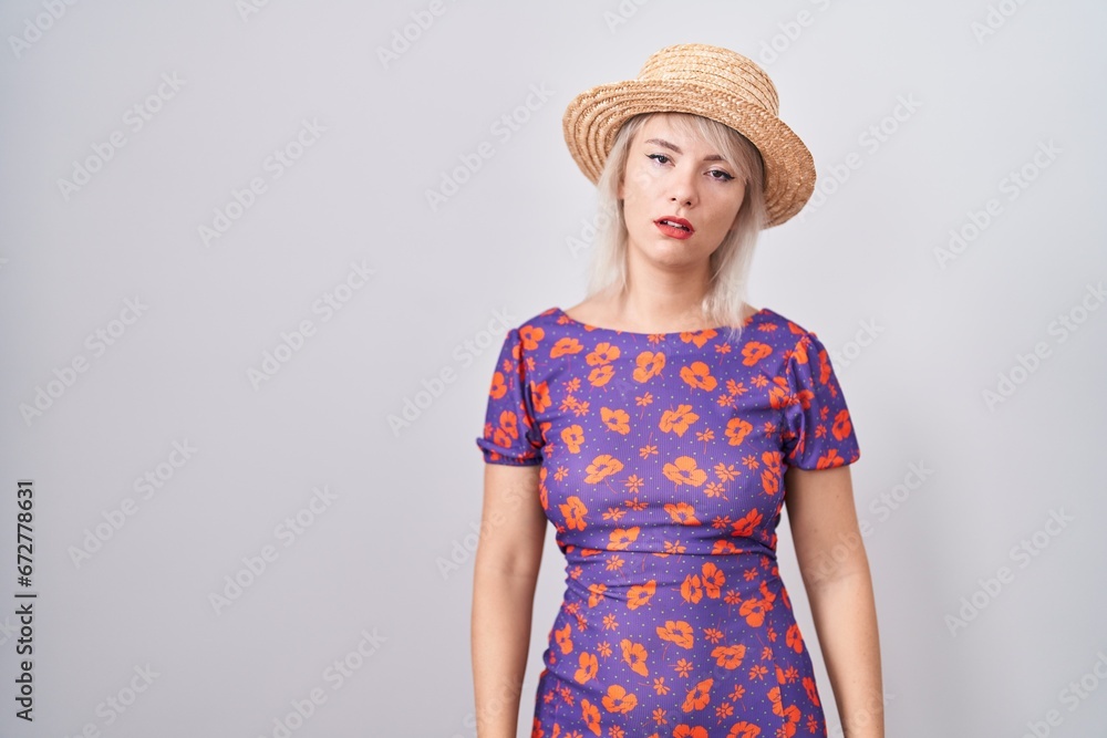 Young caucasian woman wearing flowers dress and summer hat looking sleepy and tired, exhausted for fatigue and hangover, lazy eyes in the morning. Young caucasian woman wearing flowers dress and summer hat looking sleepy and tired, exhausted for fatigue and hangover, lazy eyes in the morning.