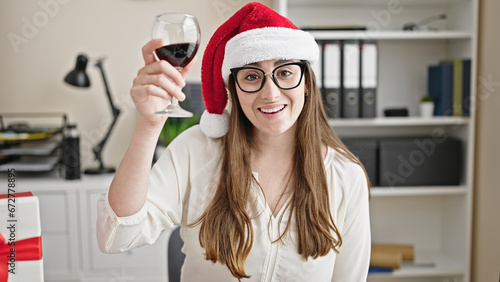 Young beautiful hispanic woman business worker celebrating christmas having video call toasting with wine at office