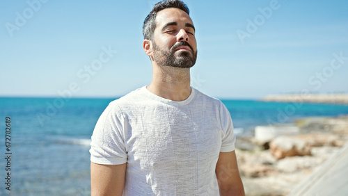 Young hispanic man breathing with closed eyes at the beach