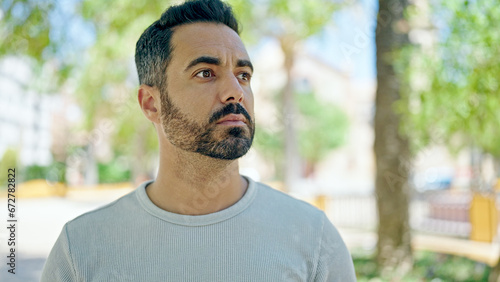 Young hispanic man looking to the side with serious expression at park