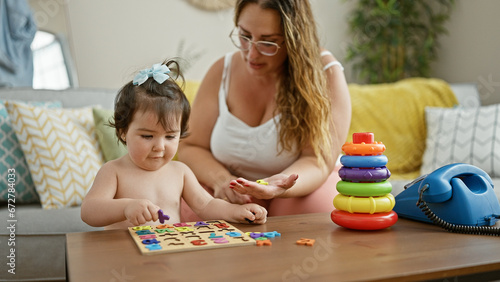 Mother and daughter share a lovely learning moment together, playing a mathematics game on the living room sofa at home