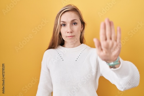 Wallpaper Mural Young caucasian woman wearing white sweater over yellow background doing stop sing with palm of the hand. warning expression with negative and serious gesture on the face. Torontodigital.ca