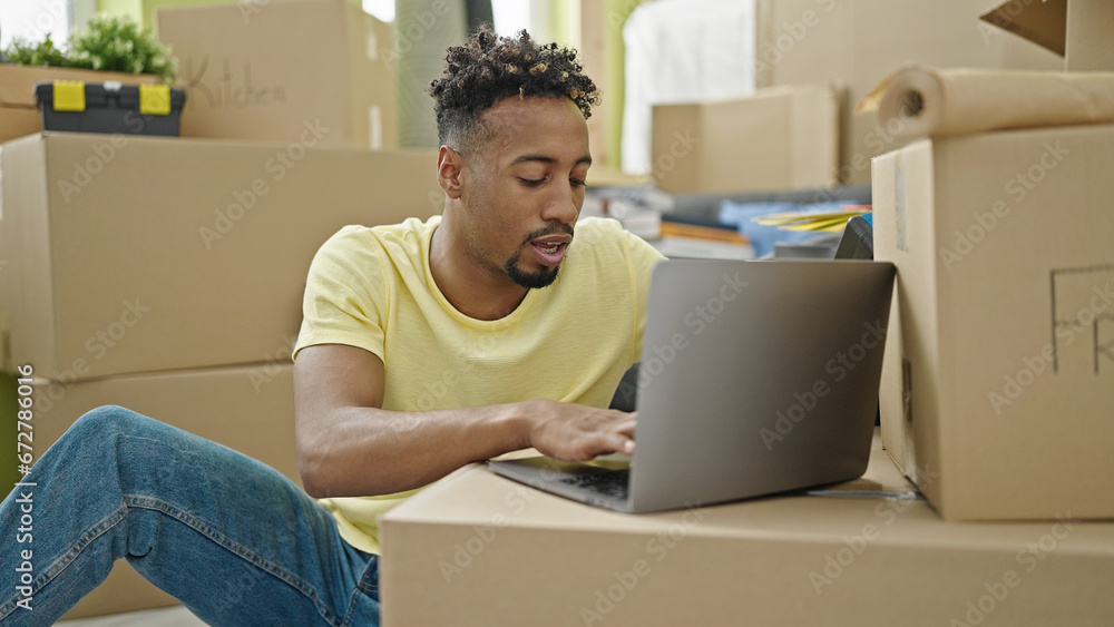 African american man using laptop sitting on floor at new home African american man using laptop sitting on floor at new home