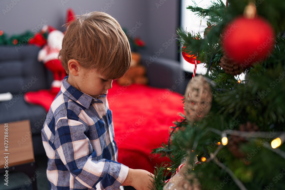 Adorable hispanic boy decorating christmas tree at home
