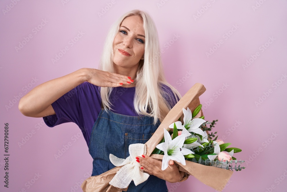 Caucasian woman holding bouquet of white flowers cutting throat with hand as knife, threaten aggression with furious violence